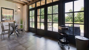 A spacious room with large windows, a dining area with chairs, a table, and a trash can. - Lush holiday home with a private Hot Tub (Zeeland)