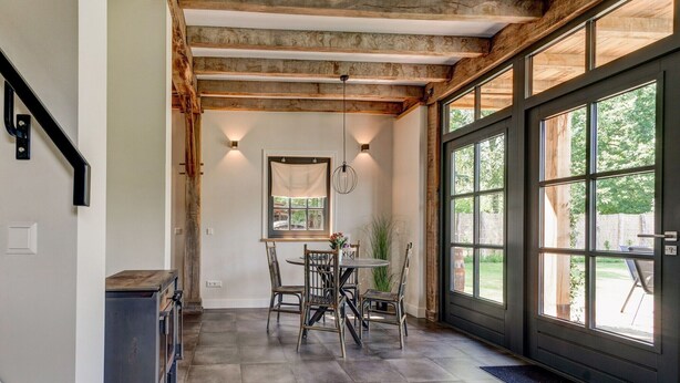 A cozy interior with a stone floor, a dining area with chairs, a table, and a fireplace. - Lush holiday home with a private Hot Tub (Zeeland)