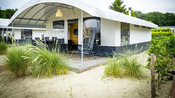 Une maison de plage moderne dotée d’un patio couvert, d’un espace salon extérieur et d’une terrasse en bois.