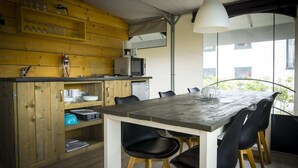 Une cuisine moderne avec des meubles en bois, une table à manger avec des chaises et une grande fenêtre offrant une vue sur l’extérieur.