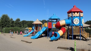 Een speelplaats met verschillende speeltoestellen, waaronder glijbanen en klimgelegenheden.