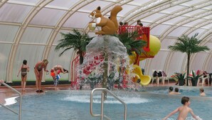 An indoor pool with a water feature, slides, and a large squirrel statue.