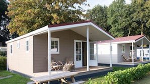 Een tweelaags stacaravan met een overdekte patio, een picknicktafel en een kleine tuin.