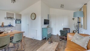 Een moderne woonkamer met een houten salontafel, een leren bank en een eethoek met een houten tafel en stoelen.