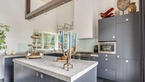 Una cocina moderna con una isla central, armarios grises y electrodomésticos de acero inoxidable.