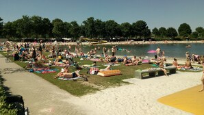Una playa concurrida con gente tomando el sol y nadando.