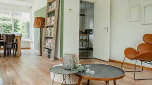 En stue med et rundt bord, en reol og et spiseområde med stole.