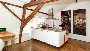 A modern kitchen with white cabinetry, wooden beams, a stainless steel range hood, and a wooden countertop. - Cottage in Leenderbos with BBQ & Garden (Leende)