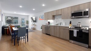 A modern kitchen with wooden cabinets, stainless steel appliances, and a dining area with a table and chairs.