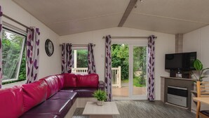 Ein modernes Wohnzimmer mit einer Ledersofa, einem Flachbildfernseher und einer Glastür, die auf einen Balkon führt.