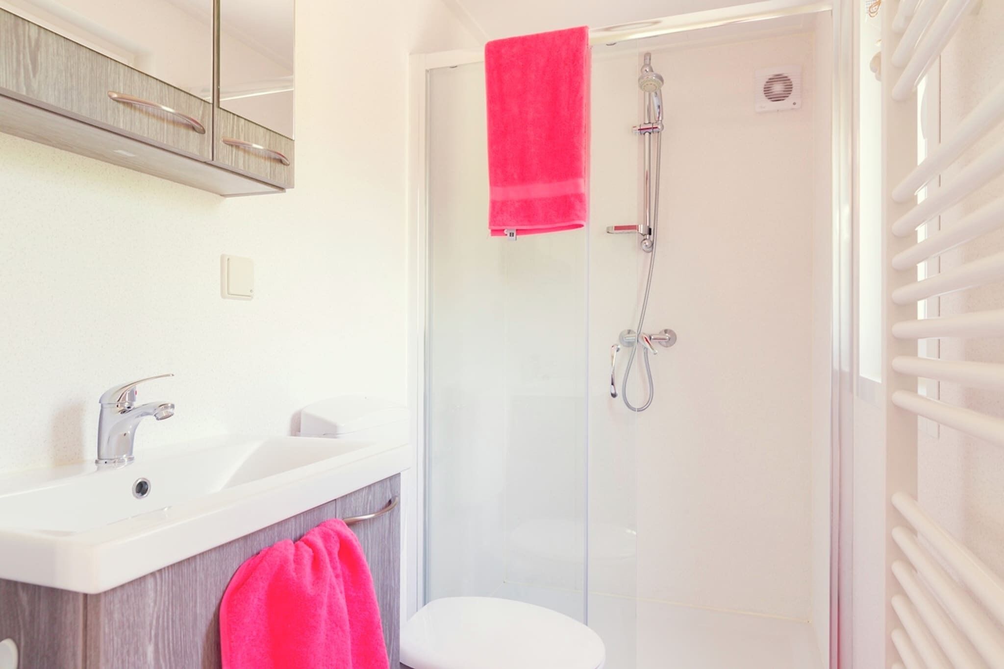 A modern bathroom with a glass-enclosed shower, a white sink, and a toilet.
