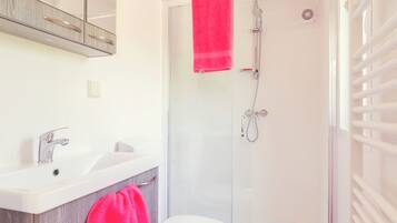 A modern bathroom with a glass-enclosed shower, a white sink, and a toilet.