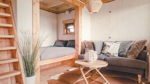 A cozy room with a bed, a sofa, a small table, and a hanging light fixture. - Tranquil Dutch Countryside (Zuna)