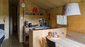 A compact kitchen with wooden cabinets, a microwave, and a hanging light fixture.