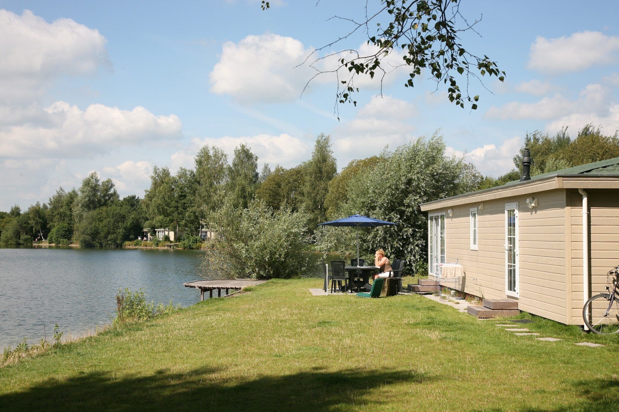Een vakantiehuis aan het meer, met een eethoek en een overdekt terras.