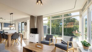 A modern living room with a wooden coffee table, grey sofas, and a TV. - Holiday home in park in Twente (Hoge Hexel)
