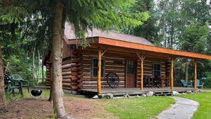 A log cabin with a porch, outdoor seating, and a grill. - Holiday Home with Garden in Den Ham (Den ham)
