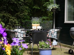 Un patio con mobiliario exterior, una mesa, sillas y plantas en macetas.