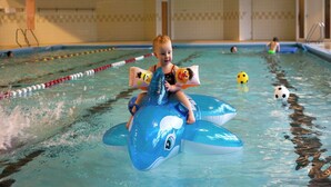 Niño sobre un tiburón inflable azul en una piscina con separadores de carril.