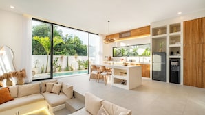 Un espacio habitable moderno tipo loft con cocina, ventanas amplias y vista a la piscina.