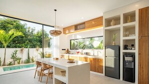 Una cocina moderna con una isla central, electrodomésticos integrados y vistas a una piscina.