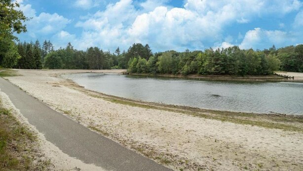 Järvenrantainen polku, jonka vieressä on hiekkaranta ja taustalla tiheä metsä.