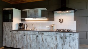 A kitchen with a central island, a built-in oven, a range hood, and a backsplash with a cow design. - Apartment in Netherlands with Scenic Meadows (Heeten)