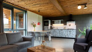 A modern living room with a wooden ceiling, a sofa, a coffee table, and a dining area with chairs. - Apartment in Netherlands with Scenic Meadows (Heeten)