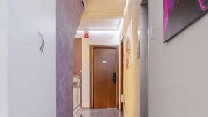 A hallway with a wooden floor, a door at the end, and a wall-mounted artwork. - Hotel 3 Comfortable Stay in Ventimiglia (Ventimiglia)