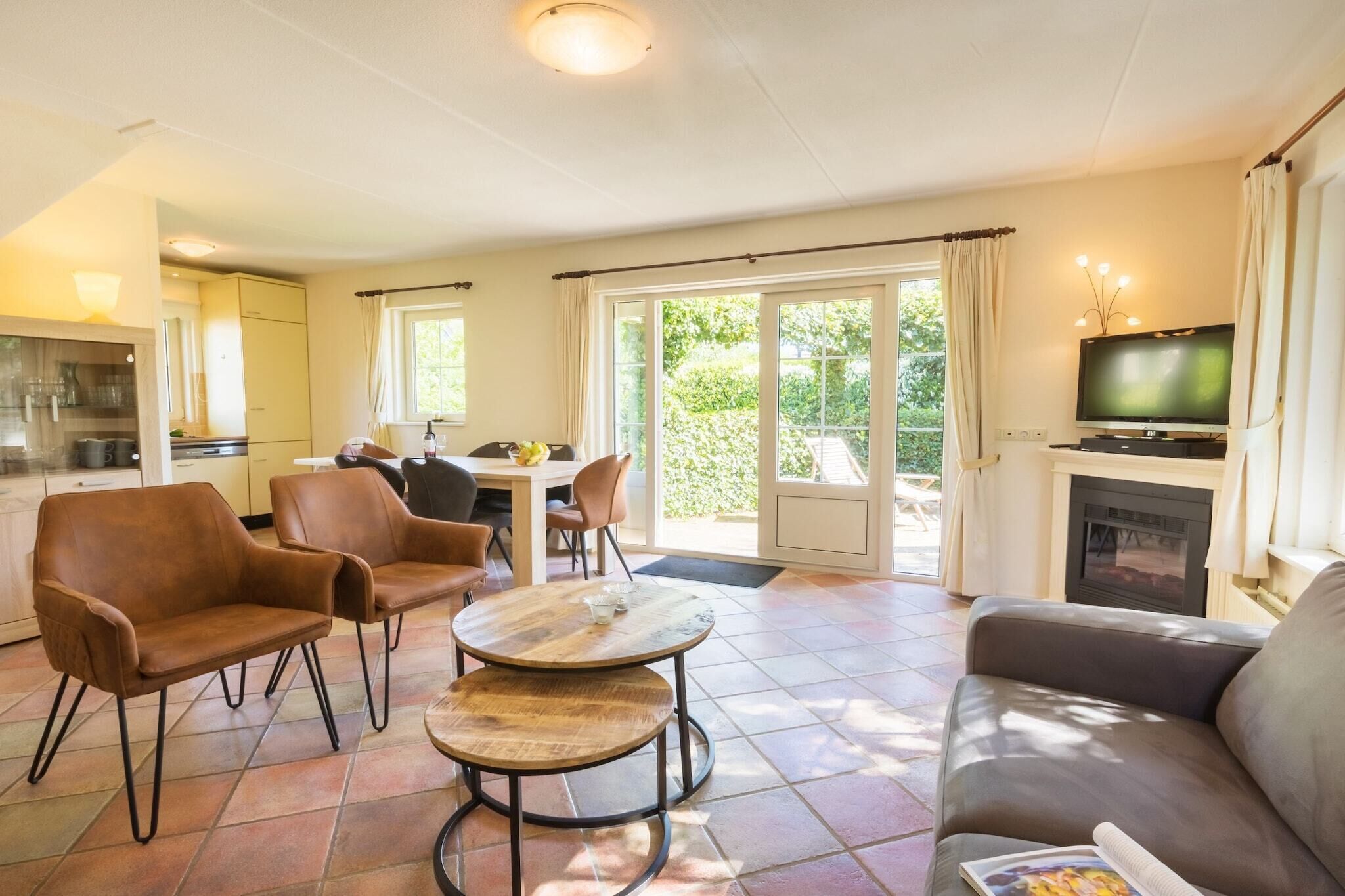 Un salon comprenant un canapé, deux fauteuils, une table basse, un téléviseur et une cheminée.