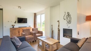 A modern living room with a sofa, armchairs, a coffee table, and a fireplace. - Luxury villa with shared pool (Paasloo)