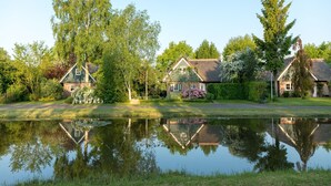 A serene lakeside setting with traditional houses, a clear reflection in the water, and lush greenery. - Luxury villa with shared pool (Paasloo)