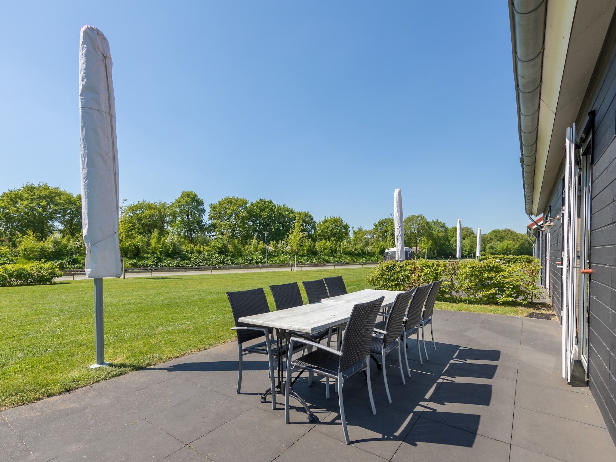 An outdoor patio with a table and chairs, a covered area, and a building in the background.