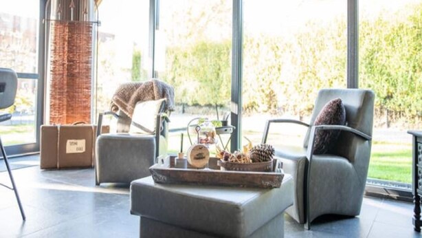 A modern living room with a fireplace, comfortable seating, and large windows offering a view of the outdoors. - Classy Holiday Home in Alphen with Garden (Alphen)