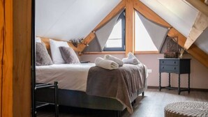 A bedroom with a sloped ceiling, a bed with pillows, a small bedside table, and a chair. - Classy Holiday Home in Alphen with Garden (Alphen)