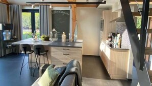 A modern kitchen with a chalkboard, a dining area with a sofa, and a staircase.