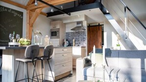 A modern kitchen with a central island, bar stools, and a dining area with a round table.