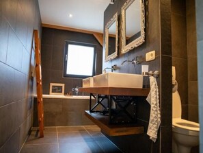 Un bagno moderno con un grande specchio, una vasca e un water.