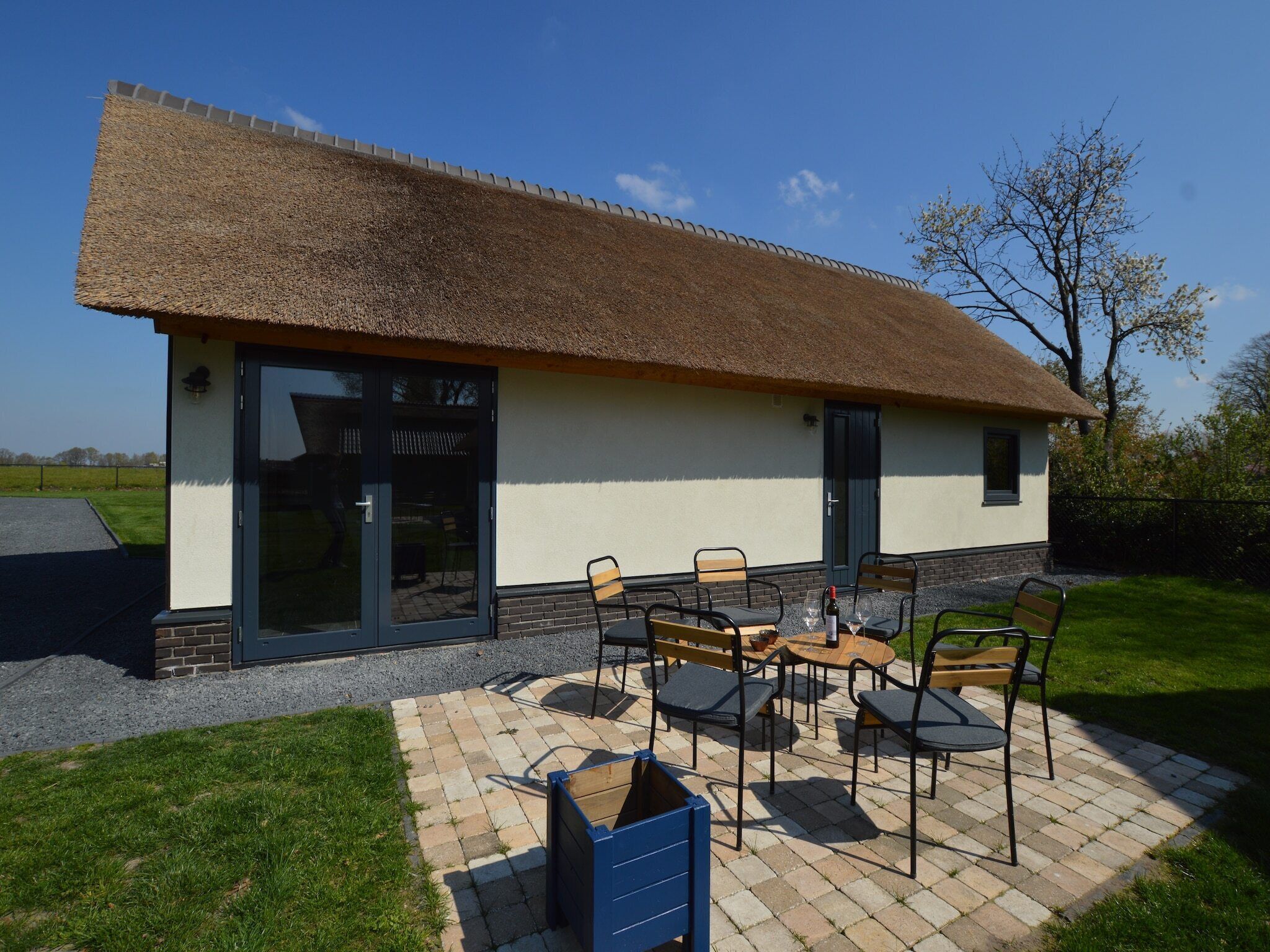 A house with a thatched roof, a patio with outdoor furniture, and a large sliding glass door.