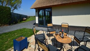 Un espace patio avec une table et des chaises, une bouteille de vin et une boîte de rangement bleue.