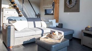 Een moderne loft slaapkamer met een slaapbank, een klein tafeltje met een mand, een houten trap en een decoratieve krans aan de muur.