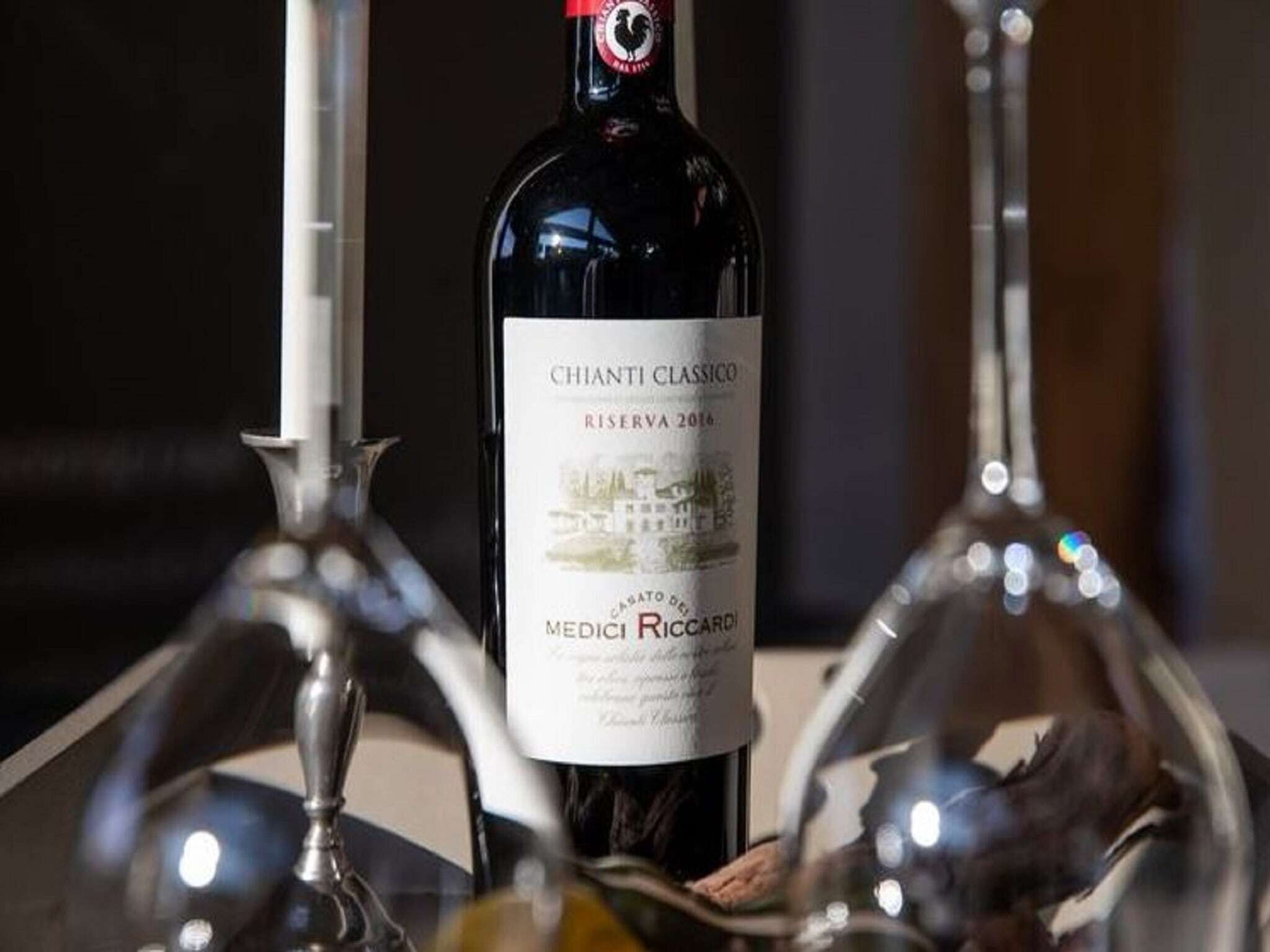 A bottle of Chianti Classico Riserva 2016 with a label featuring a vineyard and the name Medici Riccardi.