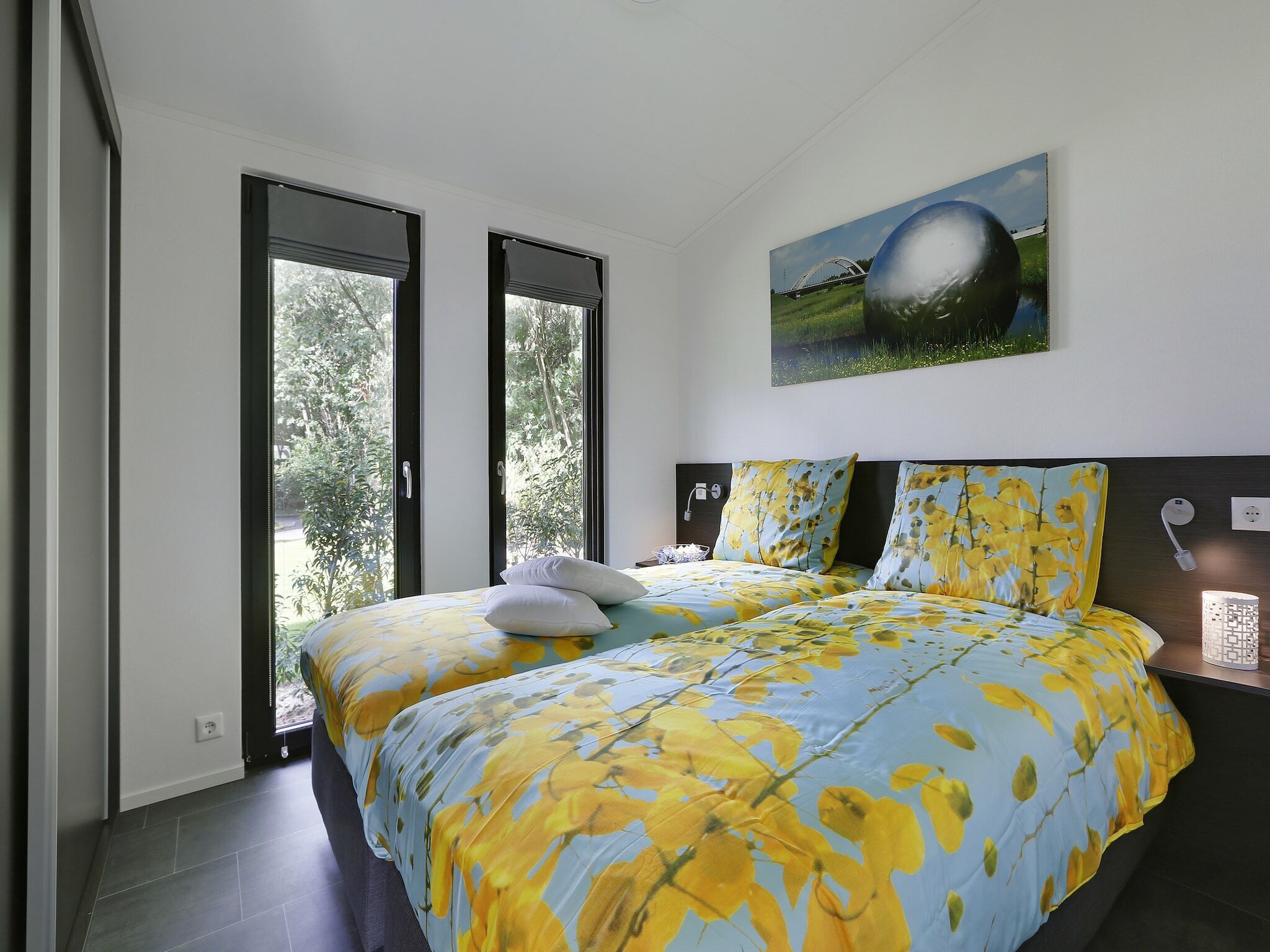 Un dormitorio moderno con una cama grande, dos ventanas y un cuadro en la pared.