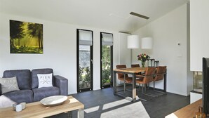 Een moderne woonkamer met een bank, salontafel en een eethoek met stoelen en een tafel.