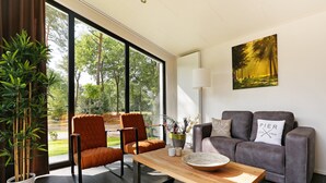 Een moderne woonkamer met een groot raam, een bank, een houten salontafel en een potplant.