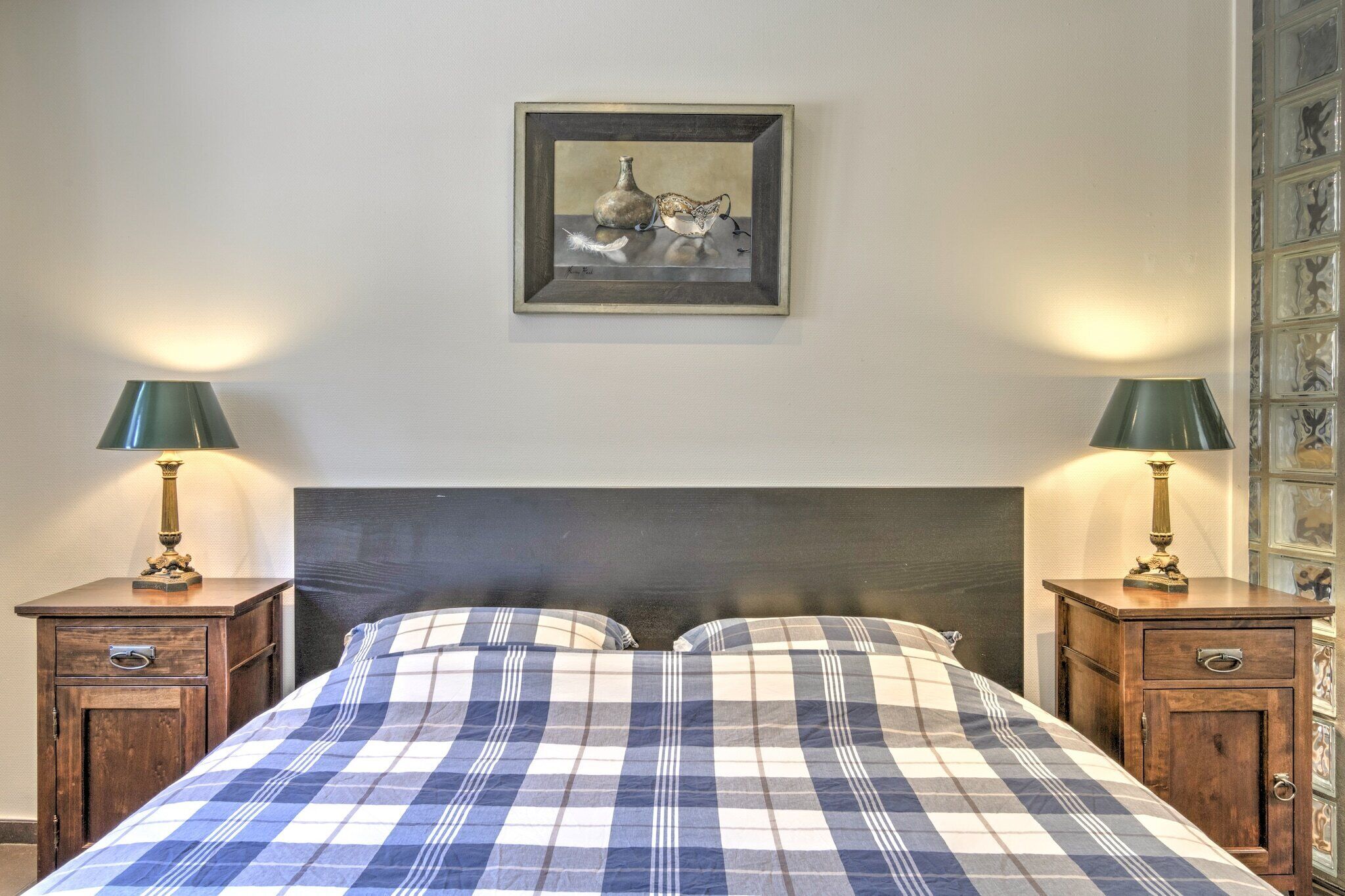A bedroom with a bed, two nightstands, and a framed artwork on the wall.