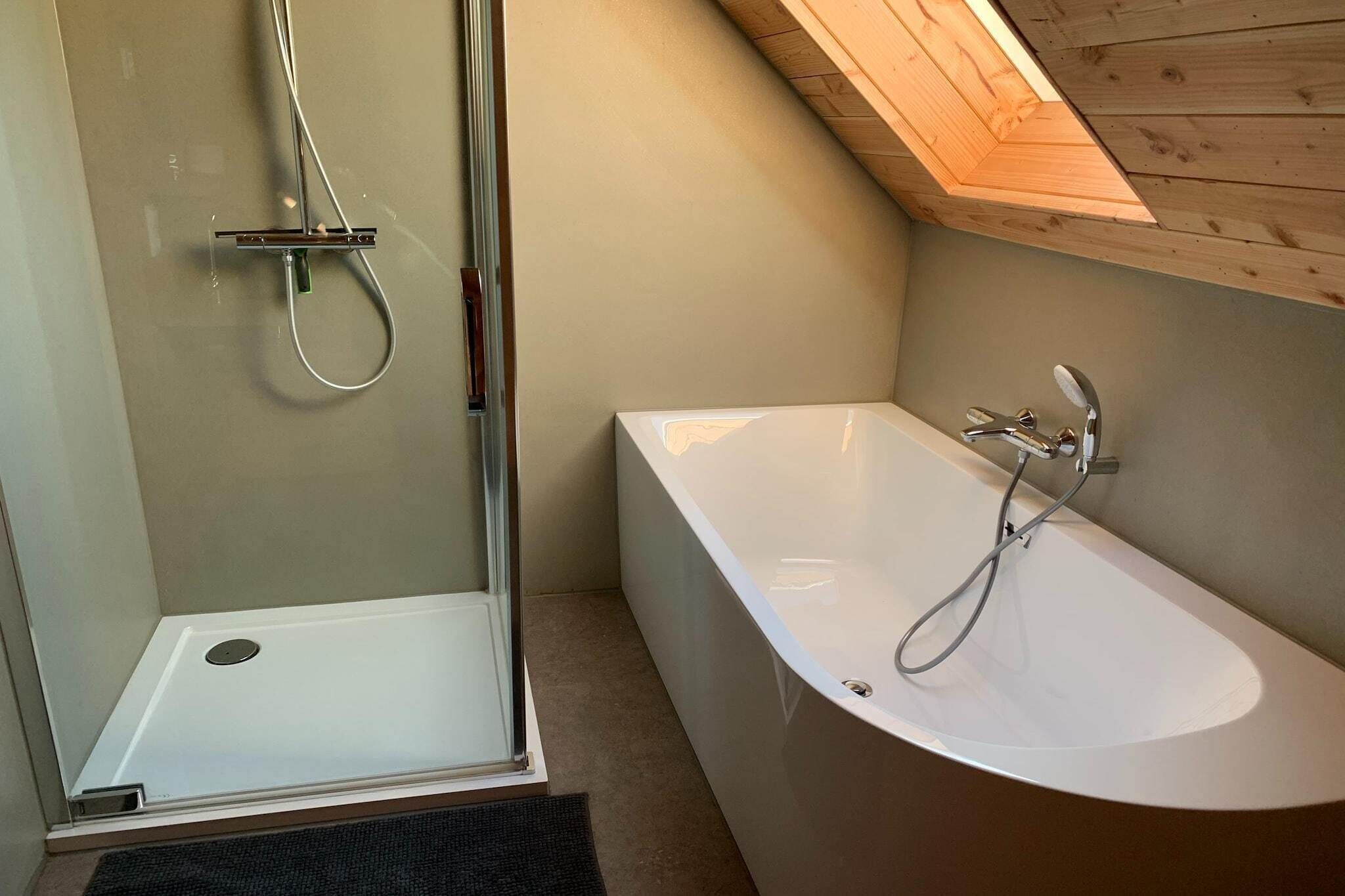 Une salle de bain moderne avec une douche à parois de verre, une baignoire sur pieds et un plafond en bois.