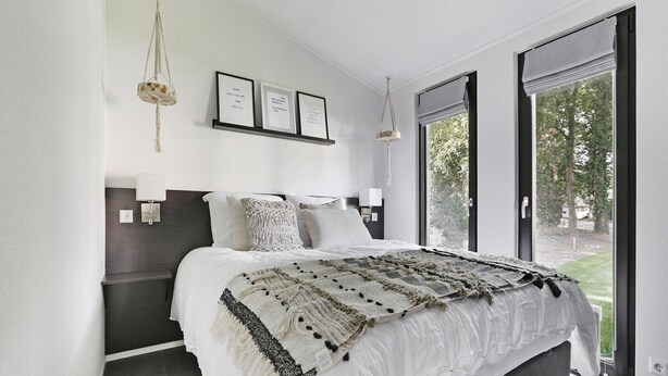 A modern bedroom with a large bed, a view of the outdoors, and a minimalist decor. - Chalet in Zell am See near Ski Slope (Markelo)