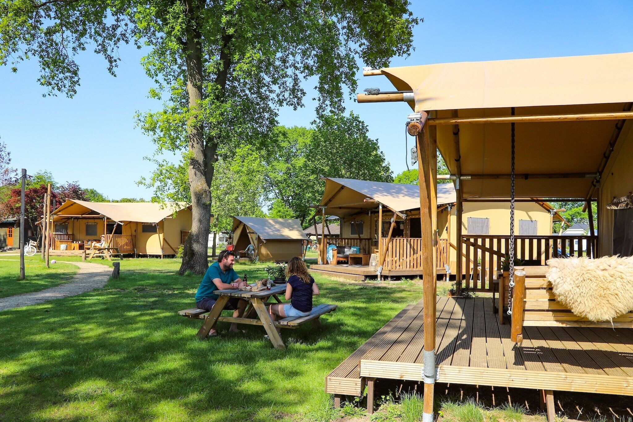 A campsite with wooden deck seating and a covered area.