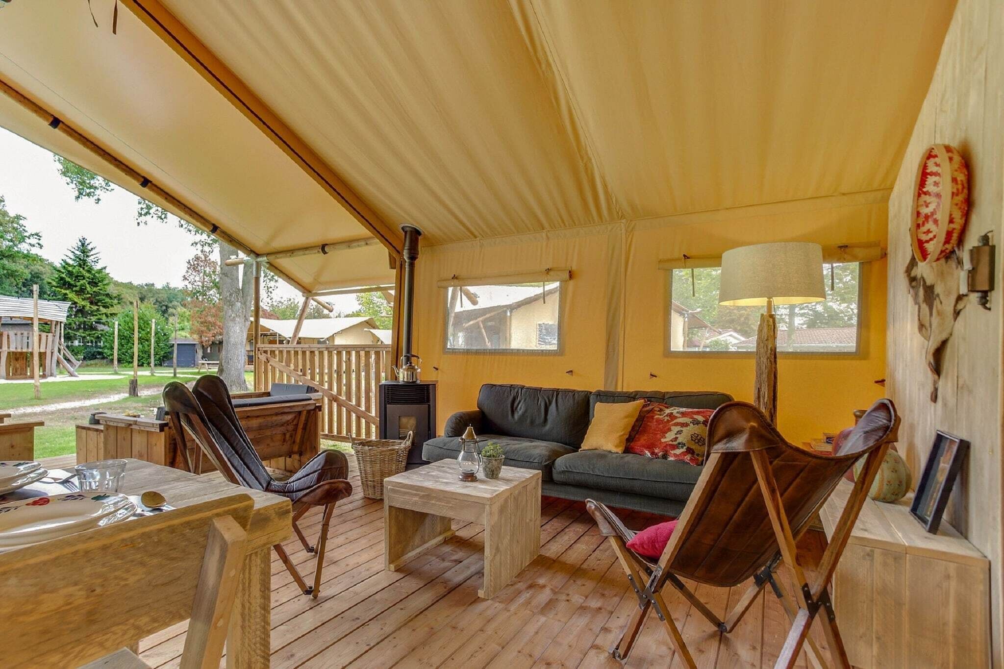 Ein gemütlicher Außenbereich mit Holztisch, Stühlen und einer Sitzecke unter einer Markise.
